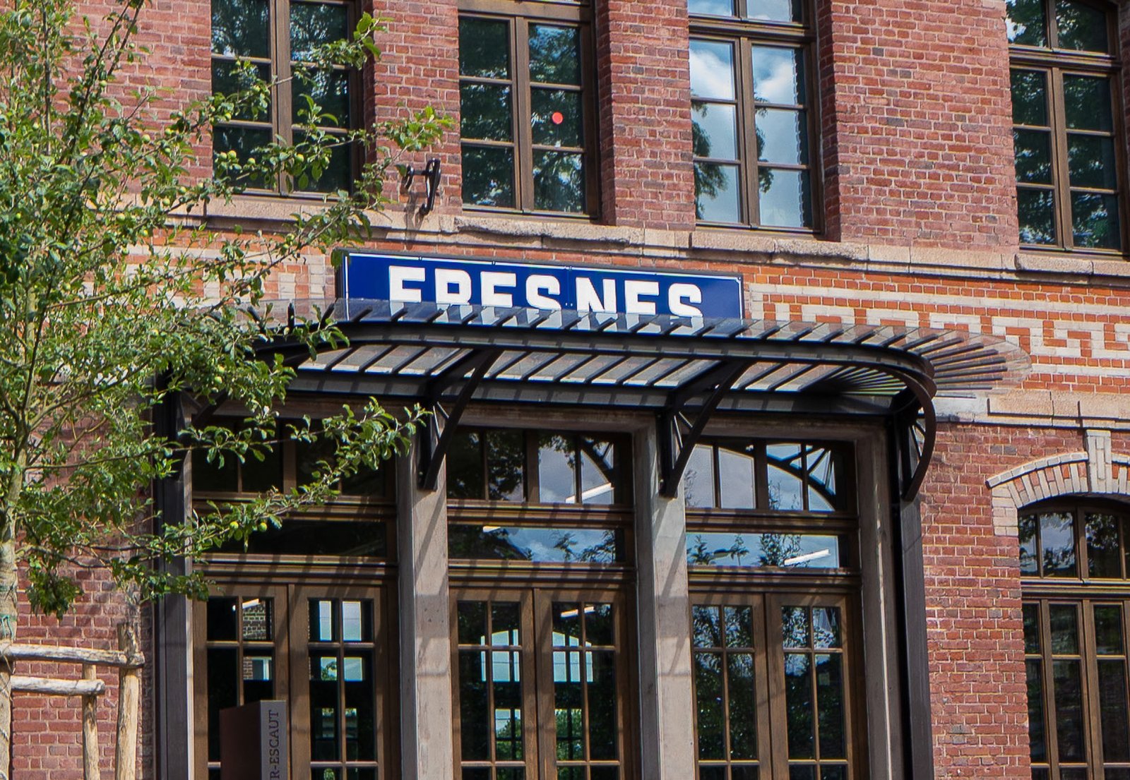 La petite marquise courbe au-dessus des portes d'entrée, sous la plaque émaillée « Fresnes »