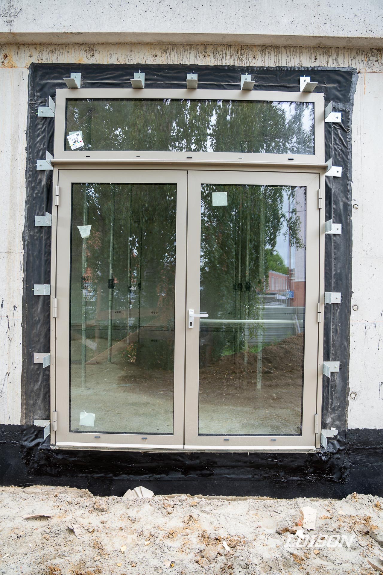 Porte vitrée à deux vantaux et imposte, entourée de sa membrane d'étanchéité à l'air