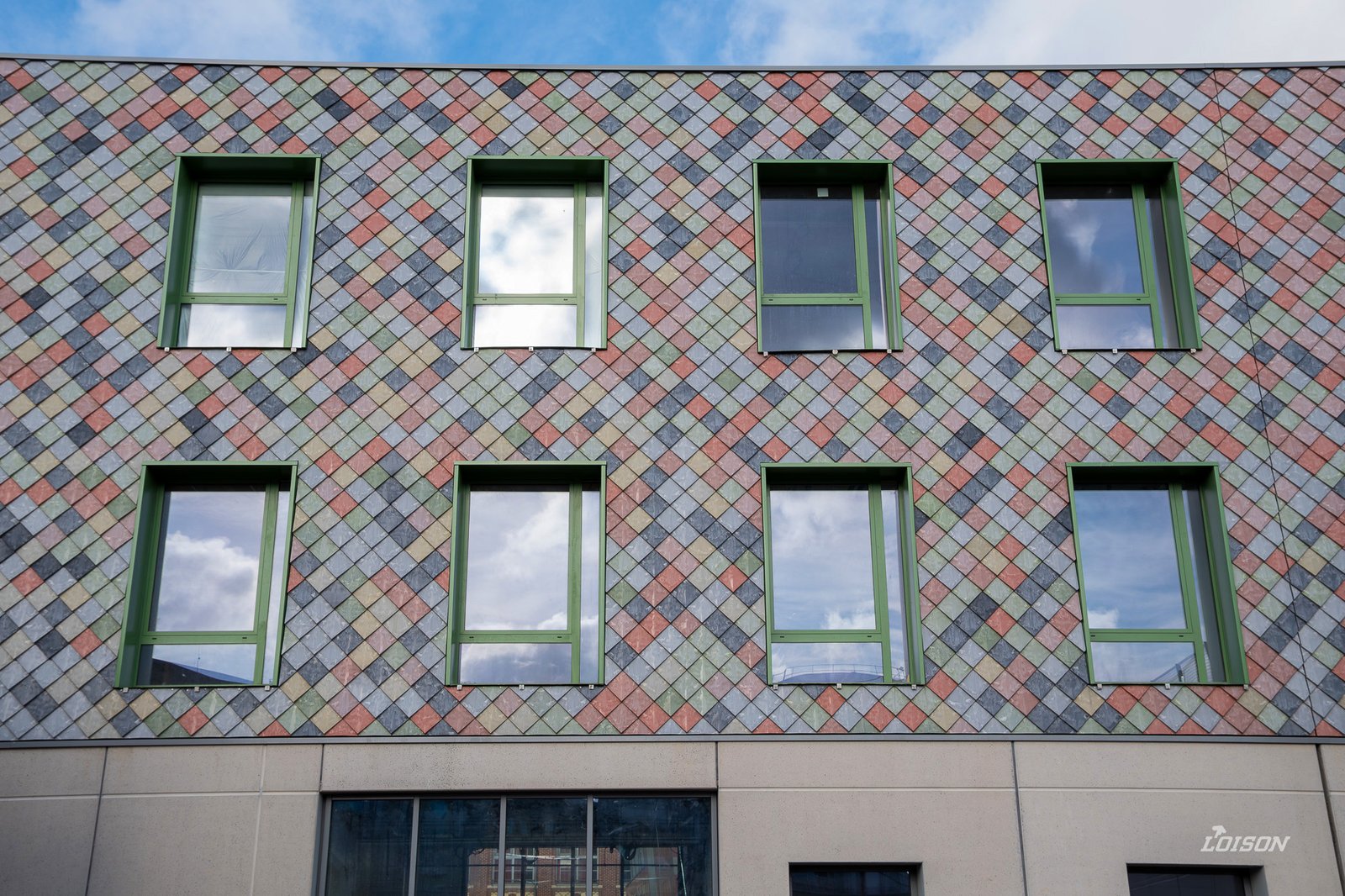 [Description de la photo, ex. : Fenêtres aluminium vertes sur la façade en tuiles colorées]