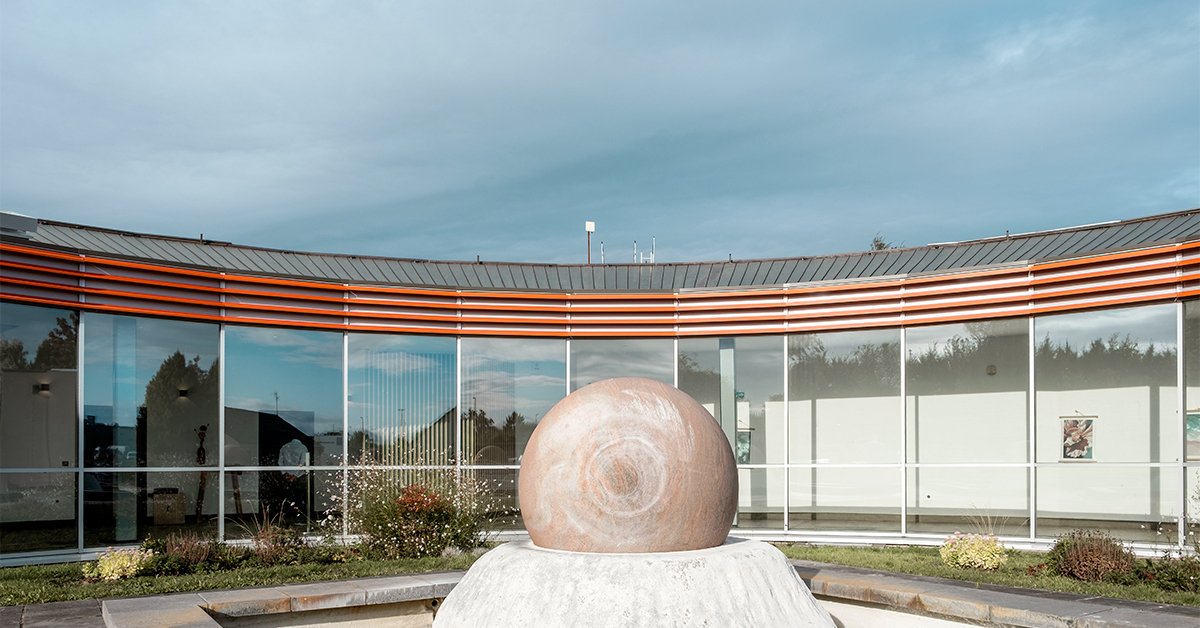 Crématorium - Herlies Le patio et sa sphère en pierre, devant le mur-rideau courbe et ses brise-soleil