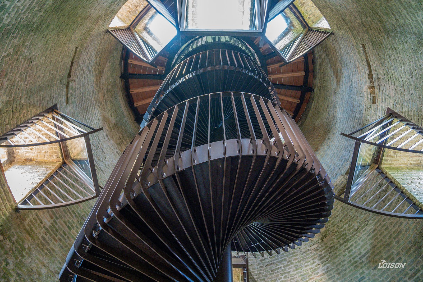 L'escalier hélicoïdal vu d'en bas, entouré des miroirs installés à 45° dans les baies du moulin